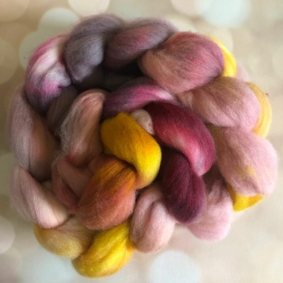 A braid of fiber featuring reds and pinks, yellow and grey.