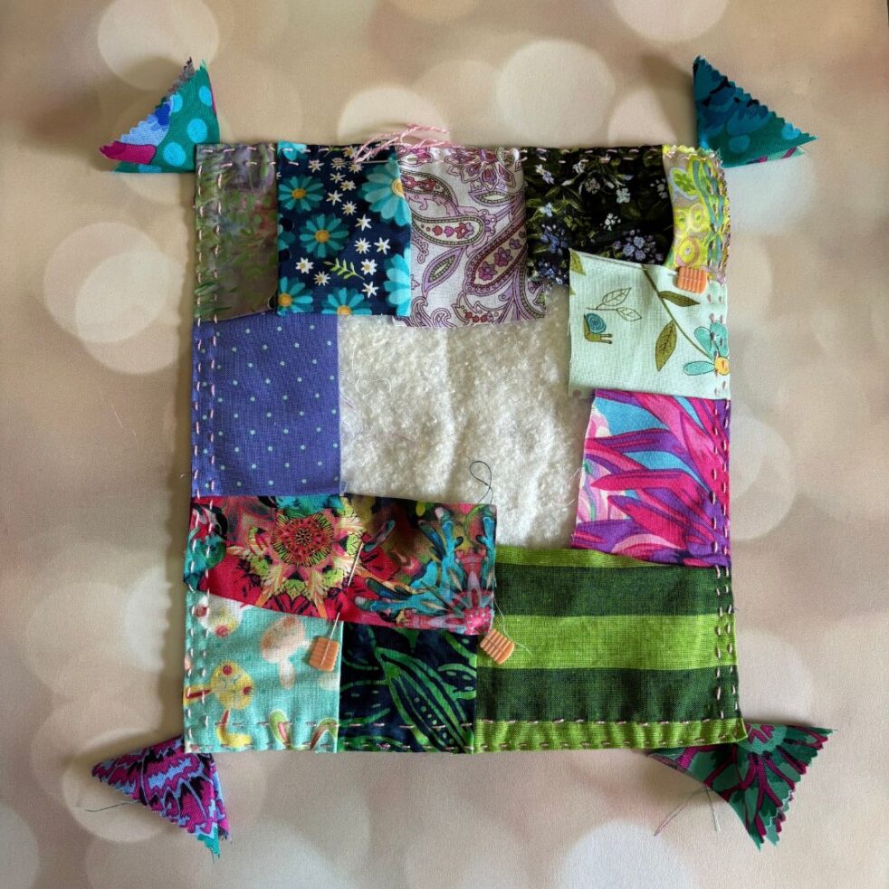 A patchwork Kawandi quilt in green, pink, blue and purple